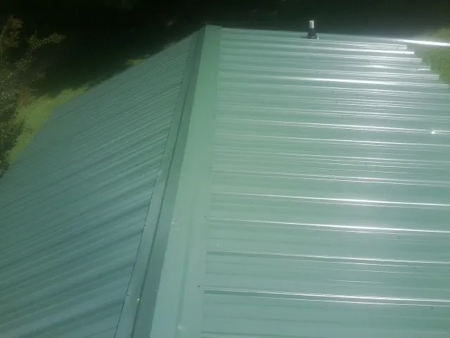 New green metal panels meeting at the ridge of a roof — Flat Roof Repair work by our crew in Barton