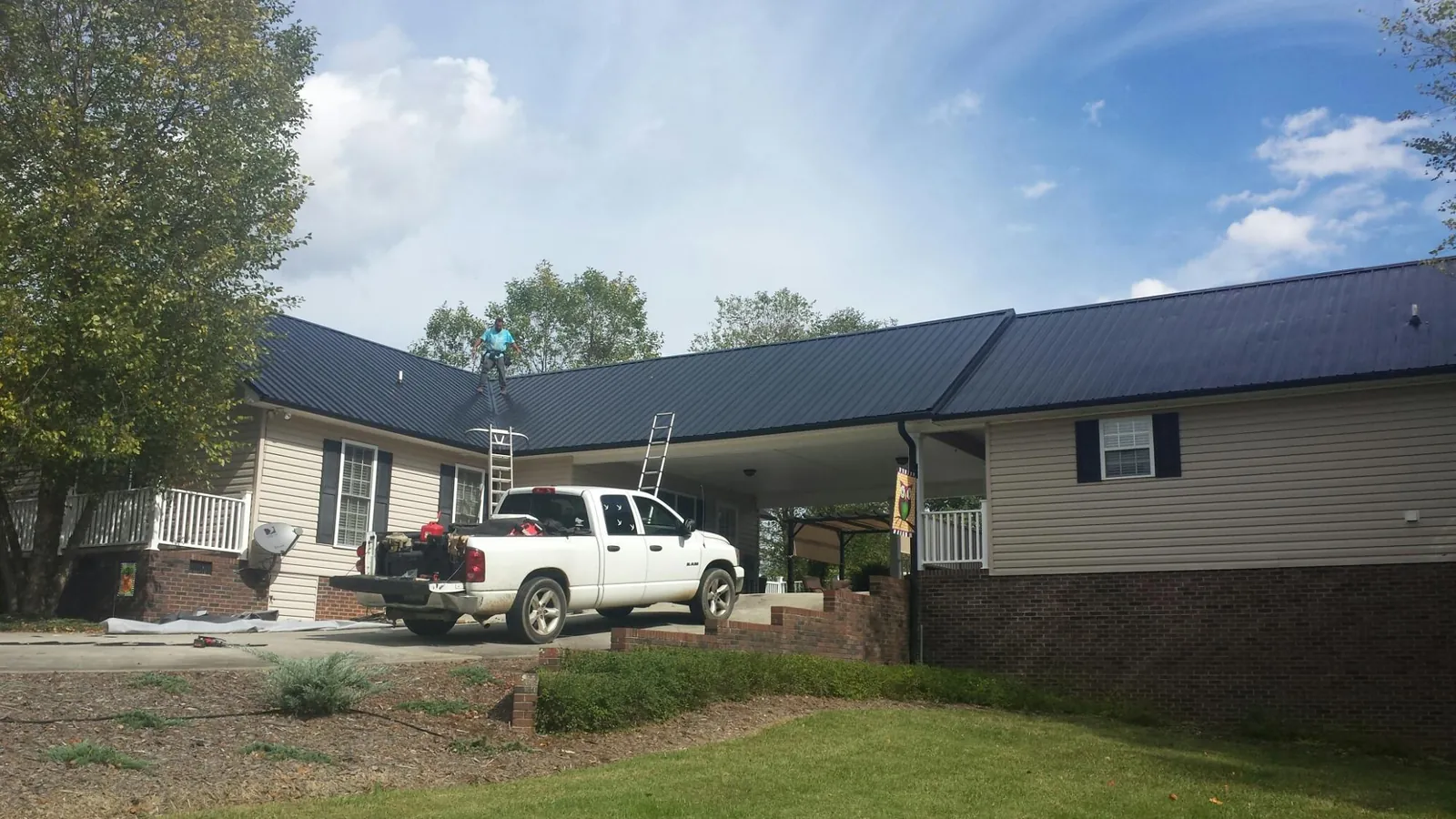 Black metal roof over a home and attached breezeway with ladders set in Barton